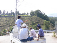 軽トラックの荷台に乗り、受信機でサルの位置を特定している写真