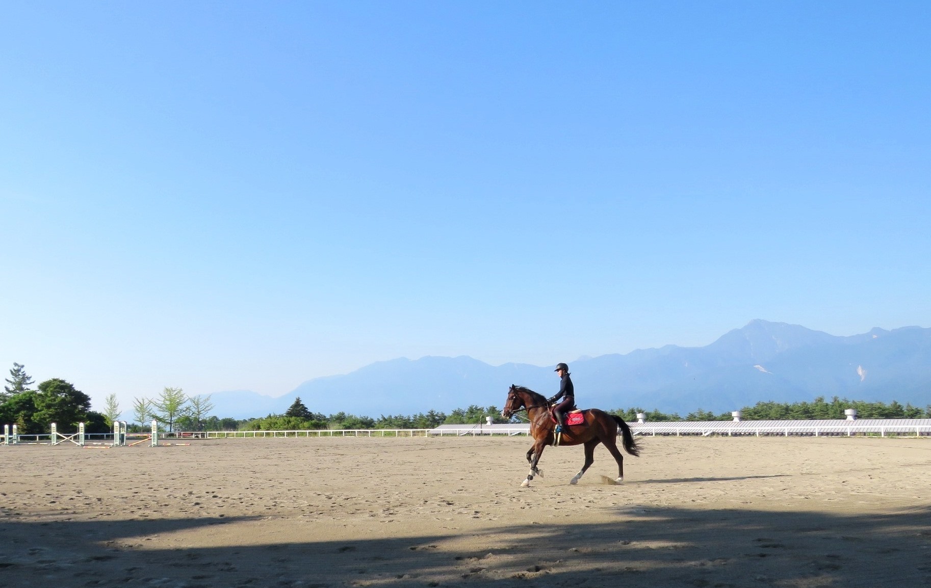 高低差のある馬術競技場の馬場では、背景が空と南アルプスという絶景