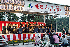ふるさと祭りの舞台で楽器演奏している写真