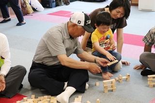 積み木で遊ぶ高齢者と親子